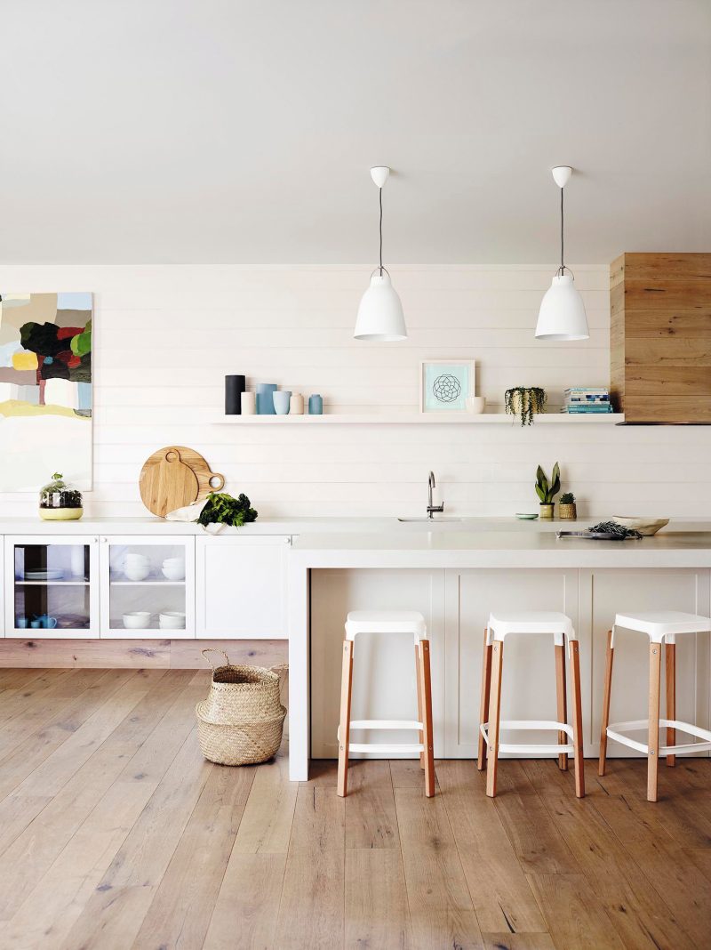 Cocina con isla y pared de lamas horizontales en tono blanco perlado y pavimento de lamas de madera